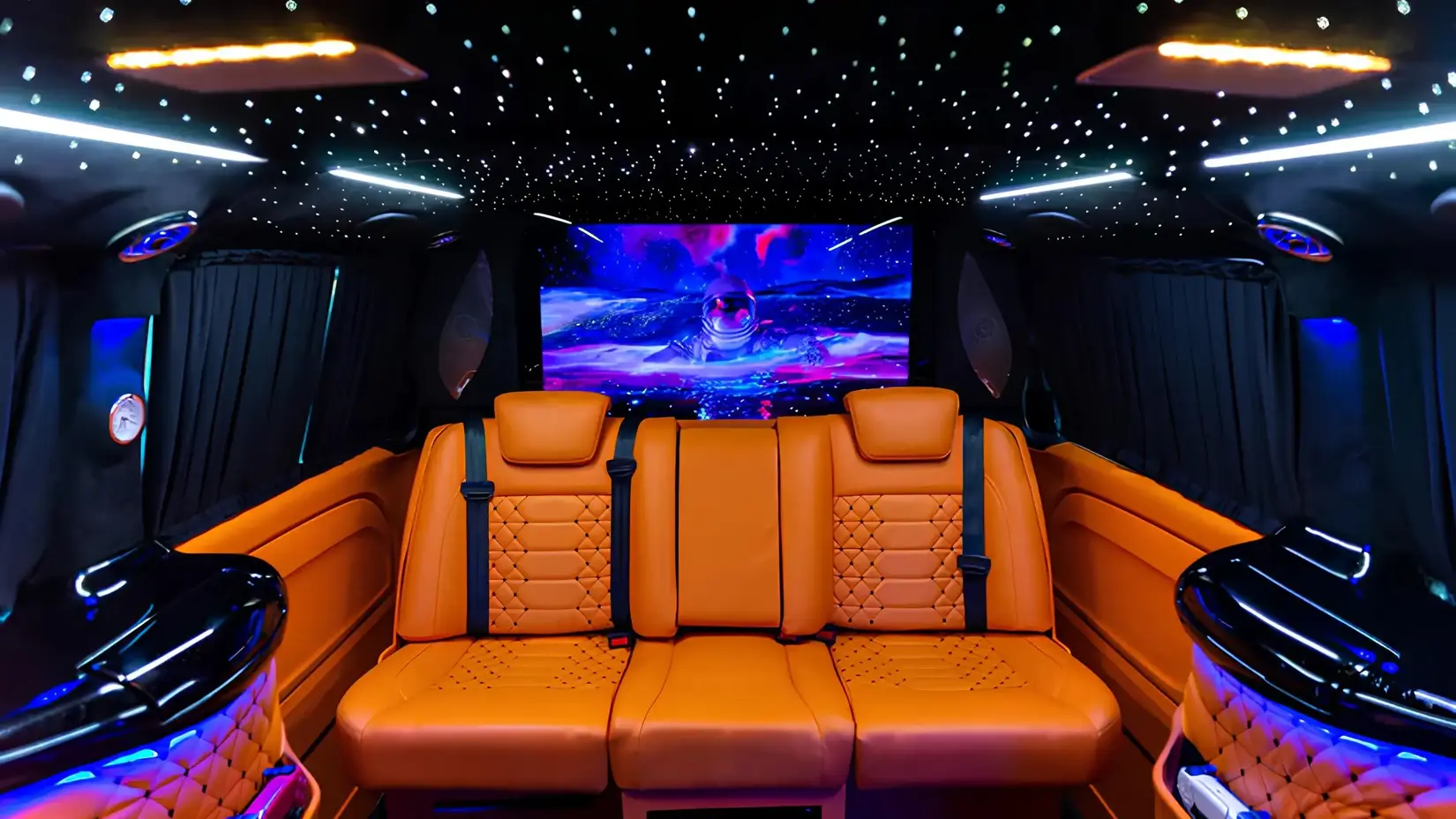 Custom VIP Mercedes minivan interior featuring orange leather seats, ambient lighting, and entertainment system.