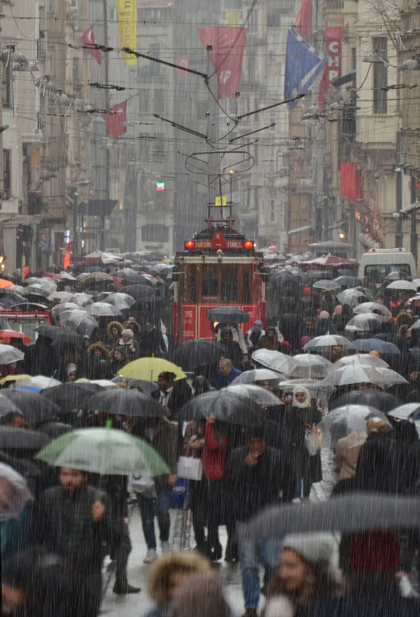 Pedestrians with umbrellas beside a tram on a rainy Istanbul street. Rail lines kept running during the floods while roads jammed. File photo from 2018. Photo: Bozan Güzel / Pexels
