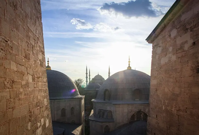 The Blue Mosque framed through Hagia Sophia's stonework - a stronger 2026 composition than the scaffolded facade itself. Photo: M. PINARCI / Wikimedia Commons / CC BY-SA 3.0